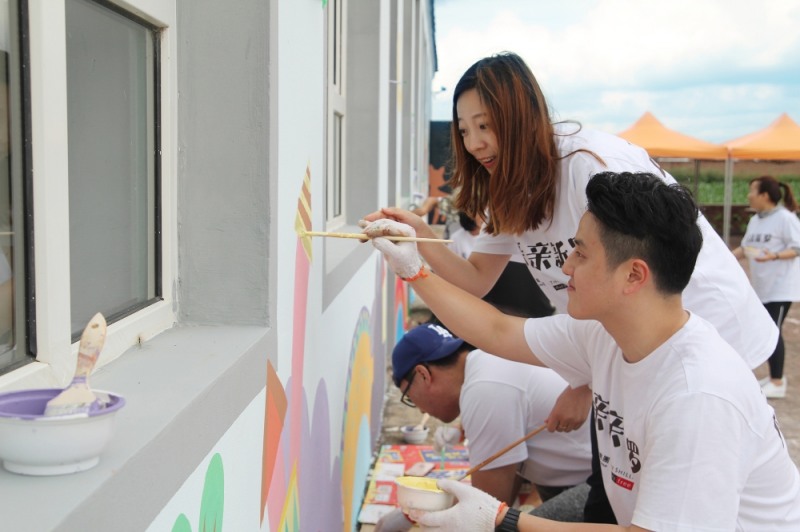 호텔신라 임직원들이 노후화된 학교 외벽을 정리한 후 밝은 색감으로 다시 그림을 그리고 있다. /사진제공=호텔신라