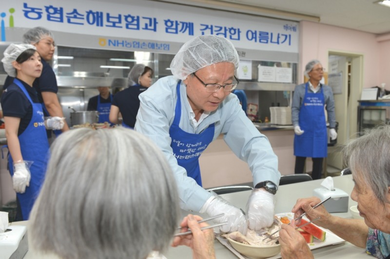 △NH농협손해보험 헤아림봉사단은 23일, 서울 서대문구 소재 서대문장애인종합복지관을 찾아 ‘여름나기 삼계탕 나눔’ 봉사활동을 전개했다. 오병관 대표이사(가운데)가 어르신에게 삼계탕을 대접하고 있다. / 사진=NH농협손해보험