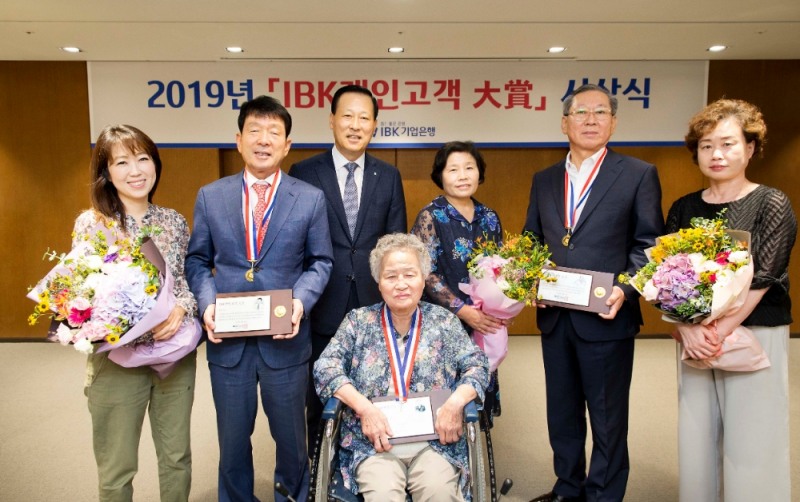 29일 서울 을지로 본점에서 김도진 기업은행장(왼쪽 세 번째), 안현자 고객(가운데), 김수영 고객(오른쪽 두 번째), 김영식 고객(왼쪽 두 번째)과 가족들이 ‘IBK 개인고객 대상’ 시상식을 마치고 기념촬영을 하고 있는 모습. / 사진= IBK기업은행