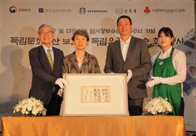 대한민국 임시정부 설립 100주년 및 광복 74주년을 기념해 스타벅스가 13일 덕수궁 중명전에서 독립문화유산 보호 및 독립유공자 자손 장학금 후원 행사를 진행했다. 스타벅스커피 코리아 송호섭 대표이사(오른쪽 두 번째)가 정재숙 문화재청장(왼쪽 두 번째)과 문화유산국민신탁 김종규 이사장(왼쪽 첫 번째)에게 독립문화유산 보호기금을 통해 구입한 도산 안창호 선생의 친필휘호 '약욕개조사회 선자개조아궁' 유물을 전달하고 있다. /사진=스타벅스코리아