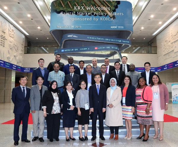 한국거래소 정근영 본부장보(상무)가 8개 신흥국 (캄보디아, 카메룬, 엘살바도르, 인도네시아, 이라크, 요르단, 키르기스스탄, 미얀마)자본시장 당국자 21명과 함께 한국거래소 신관 1층에서 기념 사진 촬영을 하고 있다./