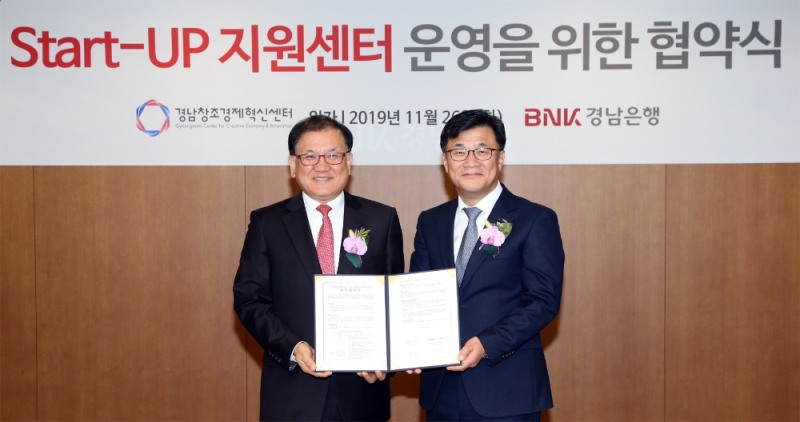 최홍영 그룹장(오른쪽)이 본점을 방문한 경남창조경제혁신센터 최상기 센터장과 ‘BNK경남은행 스타트업 지원센터 운영을 위한 업무 협약식’ 후 기념촬영을 하고 있다./사진=경남은행
