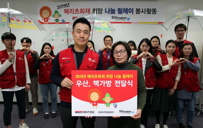 지난 26일 메리츠화재 임직원들이 투명우산 및 책가방을 만들어 김효순 중구 등대지역아동센터장(오른쪽)에게 전달하고 있다. / 사진 = 메리츠화재