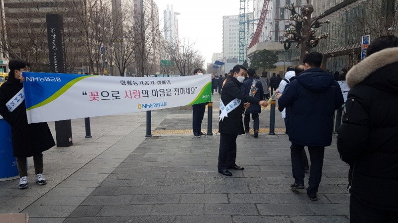 이구찬 NH농협캐피탈 대표가 14일 화훼 농가를 돕기 위한 가두캠페인 일환으로 여의도역 앞에서 시민들에게 꽃을 나눠주고 있는모습./사진=NH농협캐피탈