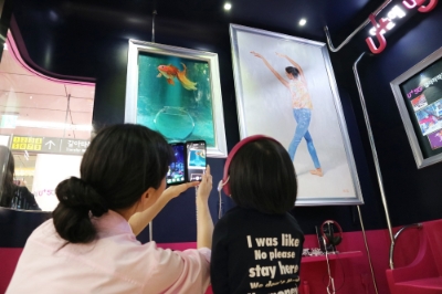 지하철 6호선 공덕역에 마련된 5G 기반 문화예술공간 ’U+5G 갤러리’에 방문한 고객이 ‘U+AR’ 앱으로 작품을 체험하고 감상하는 모습. 제공=LG유플러스