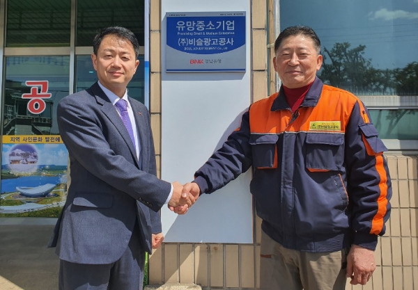 △ 장필용 BNK경남은행 현풍지점장(왼쪽)과 곽병일 비슬광고공사 대표이사(오른쪽)가 ‘유망중소기업 현판식’을 갖고 있다. /사진=BNK경남은행