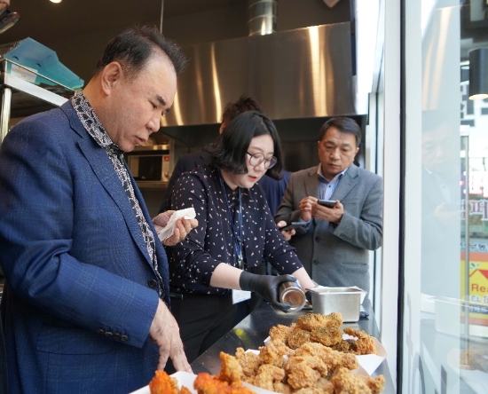 핫황금올리브치킨을 직접 시식하는 윤홍근 회장. / 사진 = 제너시스 BBQ