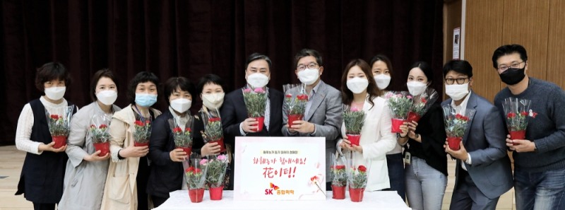 ▲ SK종합화학 나경수 사장(오른쪽에서 여섯 번째)과 서대문노인종합복지관 탁우상 관장(왼쪽에서 여섯 번째)가 생활지원사, SK종합화학 구성원들과 함께 카네이션을 들고 있다./사진=SK이노베이션