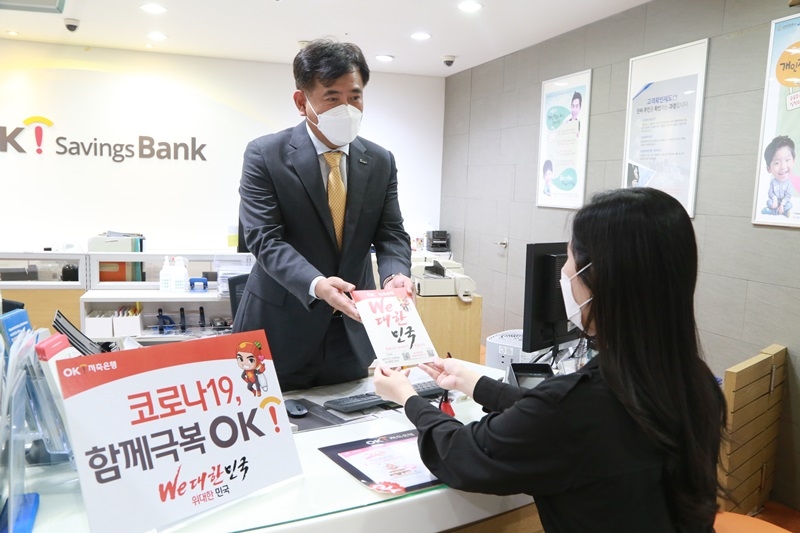 정길호 OK저축은행 대표이사(왼쪽)가 서울 세종대로에 위치한 본점 영업부에서 마스크 및 손소독제 등으로 구성된 ‘코로나19 극복키트’를 직접 고객에게 전달하며 애로사항을 청취하고 있다./사진=OK저축은행