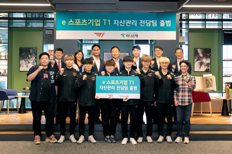 하나은행은 지난 12일 서울시 강남구소재 Club1 PB센터에서 세계적 e스포츠 기업 SK Telecom CS T1(이하 T1) 소속 선수들에 대한 자산관리 전담팀을 출범하고 출범식을 진행했다고 13일 밝혔다. ​(사진 뒷줄 왼쪽에서 네번째) 정원기 하나은행 자산관리사업단장, (사진 뒷줄 왼쪽에서 여섯번째) 김경호 하나은행 디지털금융사업본부장, (사진 앞줄 왼쪽에서 다섯번째) T1 이상혁 선수​ / 사진= 하나은행(2020.08.13)