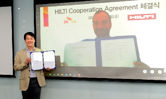 ▲ 윤혁노 SK건설 하이테크사업부문장과 라인하르트 쉰들러 힐티 부사장이 온라인 화상 협약식을 마친 후 협약서를 들고 기념촬영을 하고 있다. 사진=SK건설