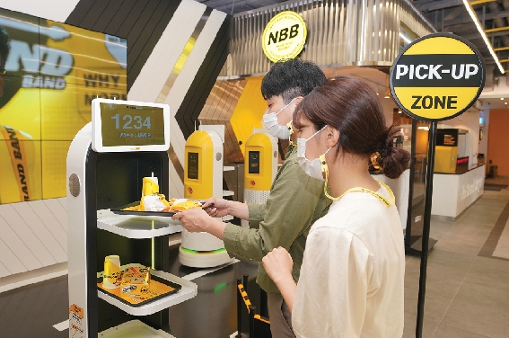 ▲ 노브랜드 버거 역삼역점에서 고객들이 서빙 로봇에서 음식을 가져가고 있다. 사진 = 신세계푸드