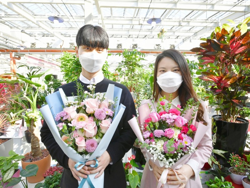 농협은행 디지털마케팅부 황재웅 계장(왼쪽)과 염유진 계장이 한국화훼농협에서 만드는 ‘희망꽃다발’을 들고 기념사진을 촬영하고 있다. /사진=NH농협은행 제공