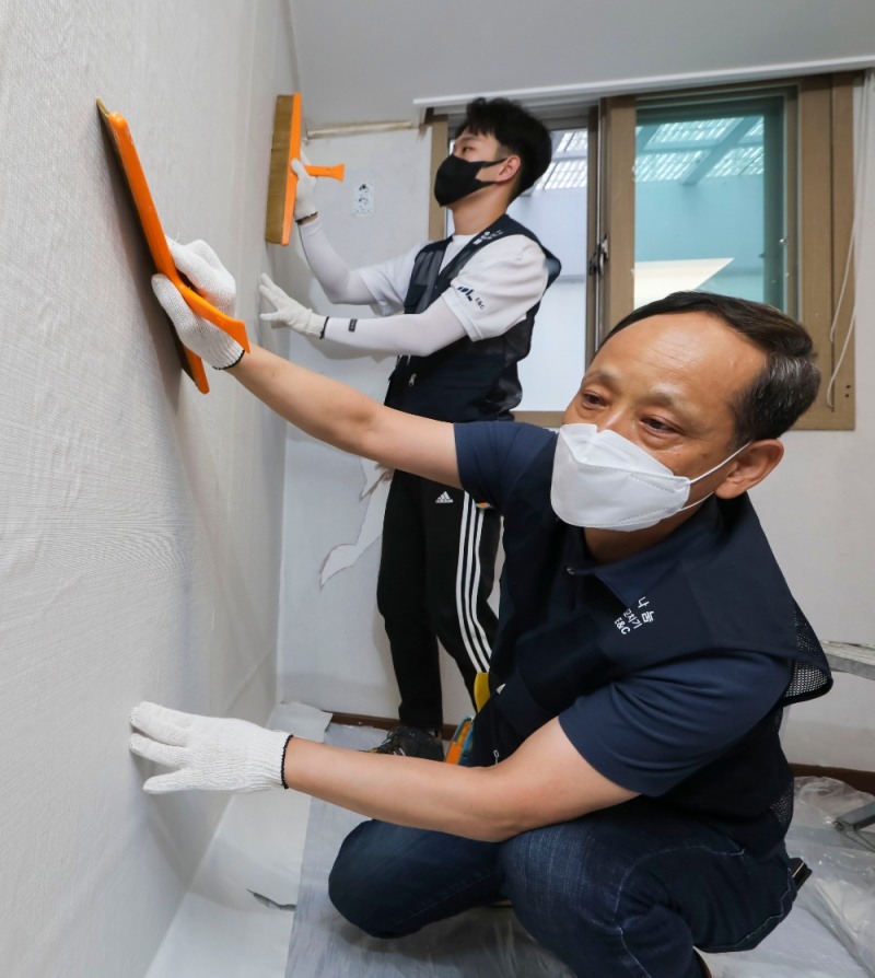 이규성 DL이앤씨 주택사업 본부장(앞)과 직원이 서울시 종로구에 위치한 선덕원에서 벽지 시공을 하고 있다. / 사진=DL이앤씨
