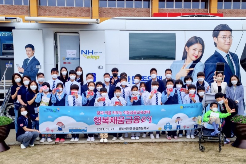 NH농협은행 임직원들과 대학생 봉사단 'N돌핀'이 지난 21일 경북 예천군 풍양초등학교를 찾아 '이동 금융교육'을 마친 뒤 학생들과 기념 촬영을 하고 있다./사진=NH농협은행