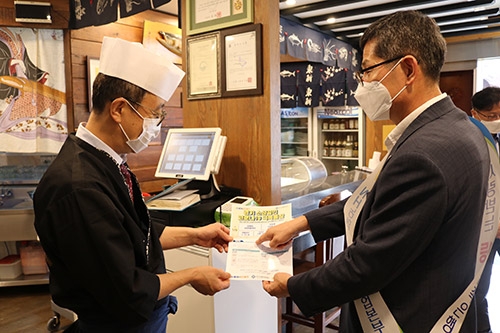 ▲ NH농협은행 경기영업본부장(사진 오른쪽)이 수원시 인계동 소재 식당에서 안내장을 전달하고 있다.