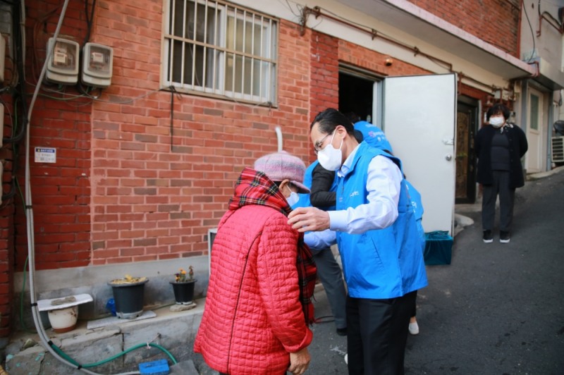 지난 29일 서울 종로구 창신2동에서 진행된 김장김치 전달 행사에 김정기 우리카드 대표이사(오른쪽)가 주민에게 목도리를 걸어주고 있다. /사진제공=우리카드