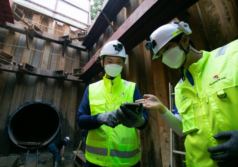 액션캠과 위치태그 등이 장착된 스마트 안전모를 착용하고 스마트폰으로 현장을 확인하는 작업자의 모습. / 사진=쌍용건설