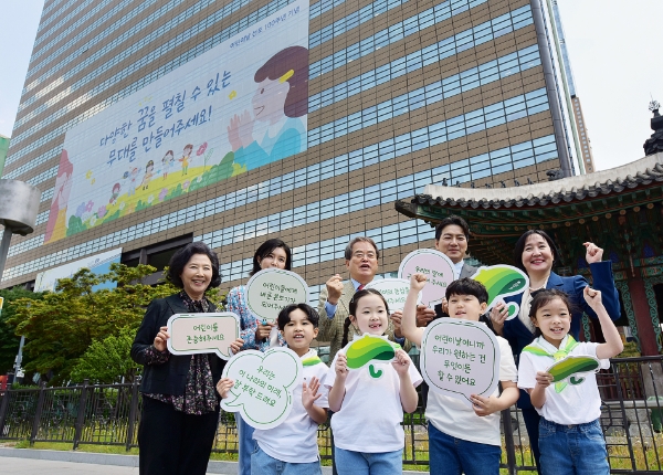 교보생명이 2일 어린이날 100주년을 맞아 서울 광화문 교보생명빌딩 외벽에 '어린이 말씀'을 담은 초대형 래핑을 선보였다. 허금주 교보생명 전무(뒷줄 맨오른쪽), 이제훈 초록우산어린이재단 회장(뒷줄 가운데)과 고두심 나눔대사(뒷줄 맨왼쪽), 송일국 홍보대사(뒷줄 오른쪽 두번째), 채정안 '아이들의 목소리' 캠페인홍보대사, 어린이들이 어린이날 100주년 래핑을 배경으로 기념촬영을 하고 있다./사진 제공= 교보생명