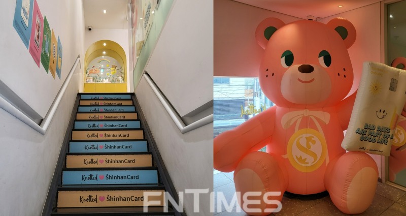 ▲ 매장 2층으로 올라가는 계단에 '노티드 신한카드(knotted Shinhancard)'라고 쓰여 있는 스티커가 붙어있다. 벽면에도 신한카드와 카페 노티드의 콜라보레이션을 알리는 포스터가 붙어있다. 언박싱 노티드 카드를 들고 있는 슈가베어 풍선이 2층 오른쪽 모서리에 자리 잡고 있다.(오른쪽) /사진제공=신혜주 기자