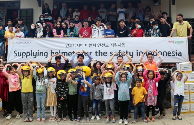 인도네시아 이륜차 교통안전 환경 조성을 위한 안전모 전달식에 참여한 KB손해보험 인니법인 관계자 및 학생들이 기념사진을 촬영하고 있다./사진=KB손해보험