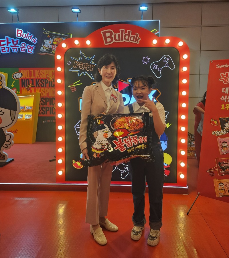 하노이에서 진행된 K-Food 페스티벌 삼양식품 부스 앞에서 삼양식품 김정수 부회장(왼쪽)과 베트남 인플루언서 자한(N.ZaHan)이 사진을 촬영하고 있다./ 사진 = 삼양식품