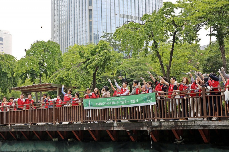 롯데물산 임직원들이 석촌호수의 수질 정화를 위해 EM흙공을 던지는 모습. /사진제공=롯데