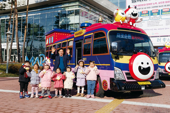 ▲ 박강수 마포구청장이 마포순환열차버스 앞에서 아이들과 함께 기념촬영을 하는 모습. 사진제공 = 마포구