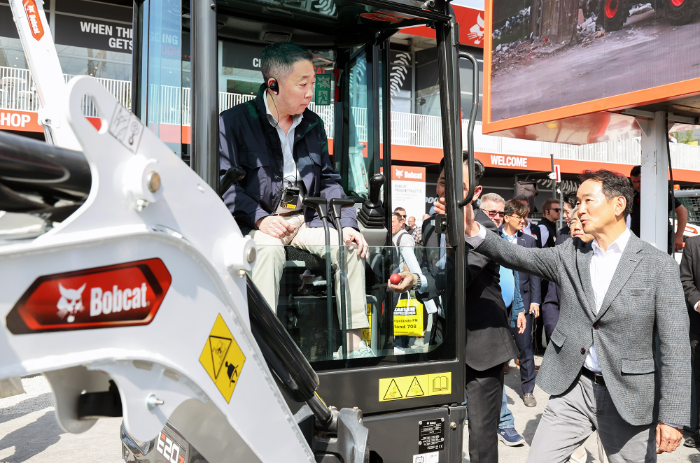 박정원 두산그룹 회장(왼쪽)이 '바우마 2025'에서 두산밥캣의 유럽시장 주력인 미니굴착기 신제품에 탑승해 스캇 박 두산밥캣 부회장(오른쪽)의 설명을 듣고 있다. /사진제공=두산그룹