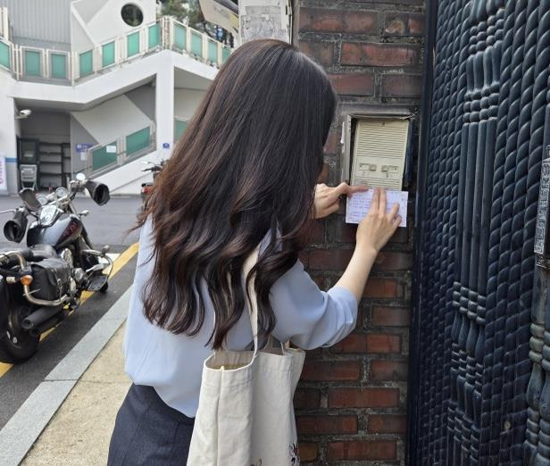 용산구청 직원이 부재중인 환급 대상자 어르신 가정 초인종에 환급 안내문을 부착하고 있다./사진제공=용산구