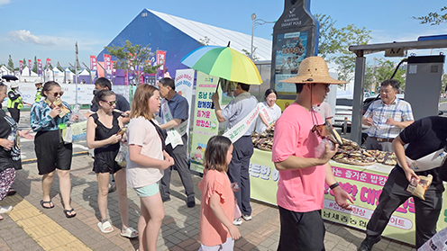 ▲ 행사 관계자들이 보령머드축제장에서 방문객들에게 쌀을 나눠주고 있다.