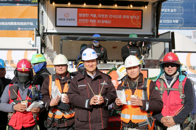김우석 한화 건설부문 대표이사(사진 가운데)가 건설현장 근로자들과 함께 ‘찾아가는 겨울간식차’의 호빵과 어묵을 즐기고 있다./사진제공=한화 건설부문