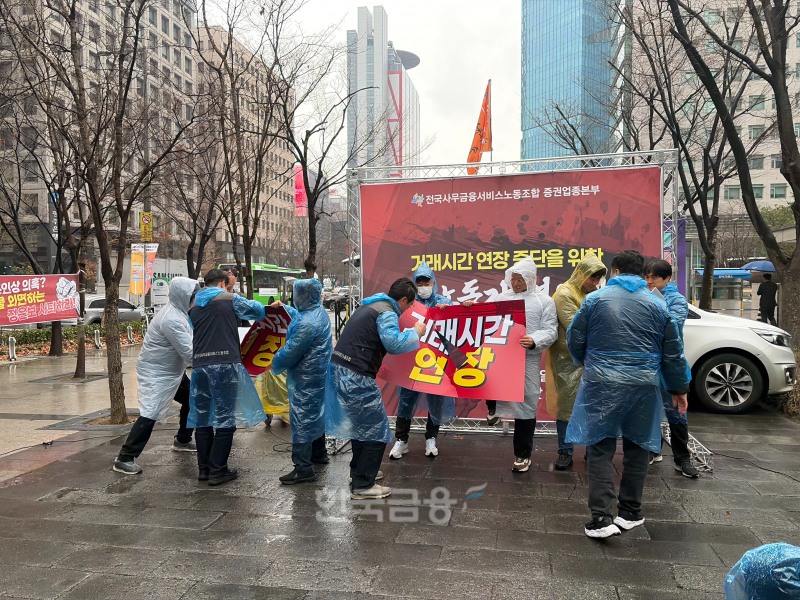 전국사무금융서비스노동조합 증권업종본부는 18일 오전 11시 30분 여의도 한국거래소 앞에서 거래시간 연장 중단을 위한 증권노동자 결의대회를 개최했다. '거래시간 연장'이 적힌 푯말을 격파하는 퍼포먼스를 펼치고 있다. / 사진=한국금융신문(2026.3.18)