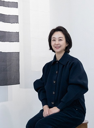 김경희 작가가 자신의 조각보 작품 앞에서 포즈를 취하고 있다.