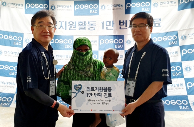 포스코건설 의료봉사단이 해외 의료 봉사활동 1만명째 의료지원을 달성하고 기념촬영을 하고 있다. 오른쪽부터 포스코건설 장원진 사회공헌그룹장과 1만명째 진료를 받은 현지인 그리고 인하대병원 가정의학과 최지호 교수. 사진=포스코건설