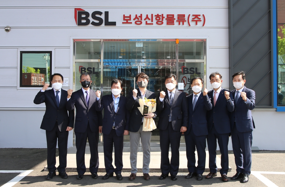 BNK경남은행 최홍영 은행장(왼쪽에서 다섯 번째)이 최병목 보성신항물류 상무(왼쪽에서 네 번째)에게 우수사원 표창패와 꽃다발을 수여한 뒤 직원들과 기념 촬영을 하고 있다. /사진제공=BNK경남은행