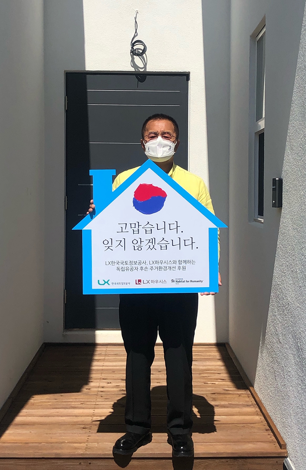 독립유공자 故 최덕주 선생의 손자 최재국 씨가 LX한국국토정보공사ㆍLX하우시스ㆍ한국해비타트가 함께 새로 만든 자택 앞에서 “고맙습니다. 잊지 않겠습니다” 문구가 적힌 패널을 들고 기념촬영을 하고 있다. /사진제공=LX공사