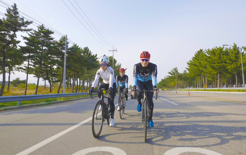 장선재 LX사이클 선수단 코치(오른쪽)와 선수들이 조아라 사이클 유튜버가 강원도 양양군 해변길에서 라이딩을 하고 있다. / 사진제공=LX공사
