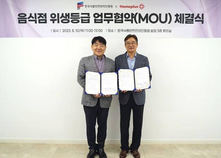 송명헌 홈플러스 안전보건관리부문장(왼쪽)과 홍진환 한국식품안전관리인증원 이사(오른쪽)가 충청북도 청주시 한국식품안전관리인증원 본원에서 업무협약 체결 후 기념촬영을 하고 있는 모습./사진제공=홈플러스