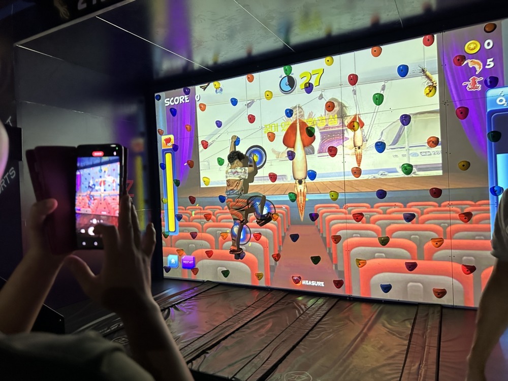 한 아동 관람객이 아스포즈 부스에 방문해 '오징어게임 AR 클라이밍' 프로그램을 체험하고 있다. / 사진제공=아스포즈