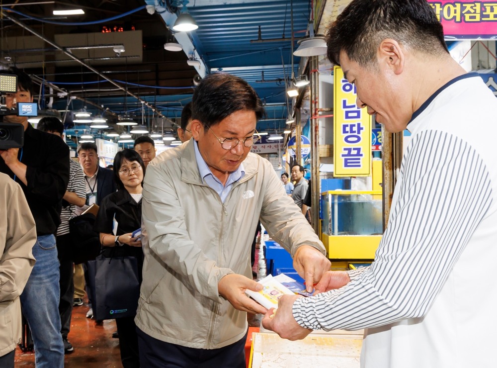 박강수 마포구청장이 마포농수산물시장에 방문해 상인에게 '안전한 여름철 수산물 즐기기 리플릿'을 배부하고 있다./사진제공=마포구