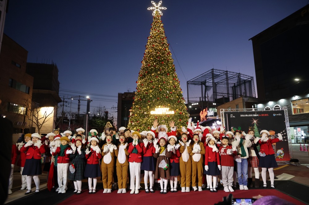 산타분장을 한 박강수 마포구청장이 레드로드 R6 대형 트리 앞에서 어린이 합창단과 기념촬영을 하고 있다./사진제공=마포구