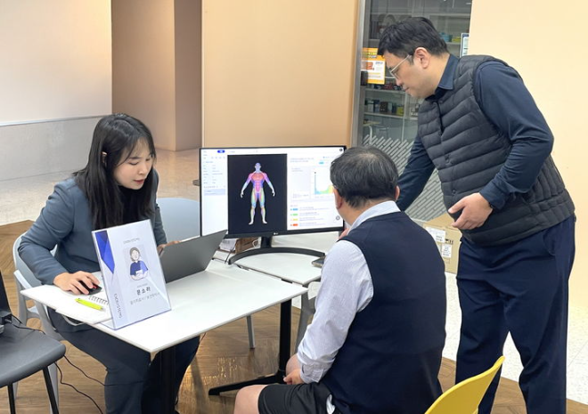 대웅제약 임직원(왼쪽)이 AI 실명질환 진단 보조 솔루션 위스키(WISKY)와 안저카메라 옵티나(OPTiNA Genesis)를 이용해 3대 실명질환 검사를 받은 후, AI 판독 결과를 확인하고 있다. /사진=대웅제약