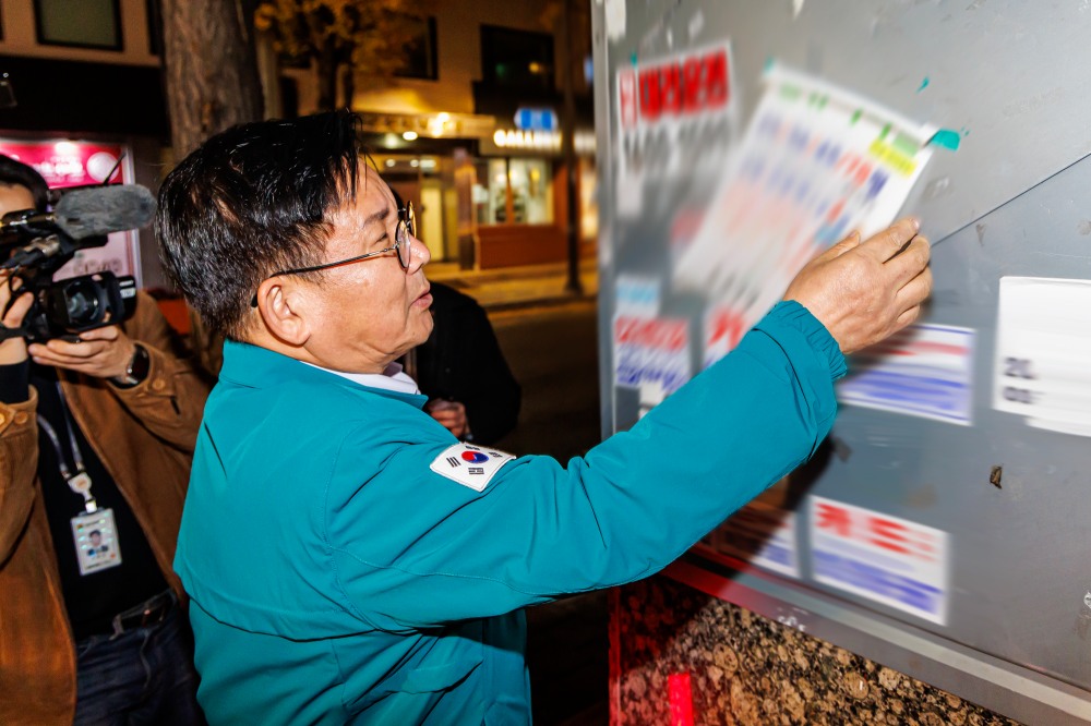 박강수 마포구청장이 레드로드 일대에 부착된 청소년 유해 불법 광고물을 제거하는 모습./사진제공=마포구
