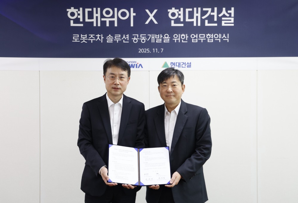 김재영 현대건설 기술연구원장(오른쪽)과 백익진 현대위아 모빌리티솔루션사업부 상무가 ‘로봇 친화형 주차솔루션 공동개발을 위한 업무협약’을 체결하고 기념 사진을 찍고 있다./사진제공=현대건설