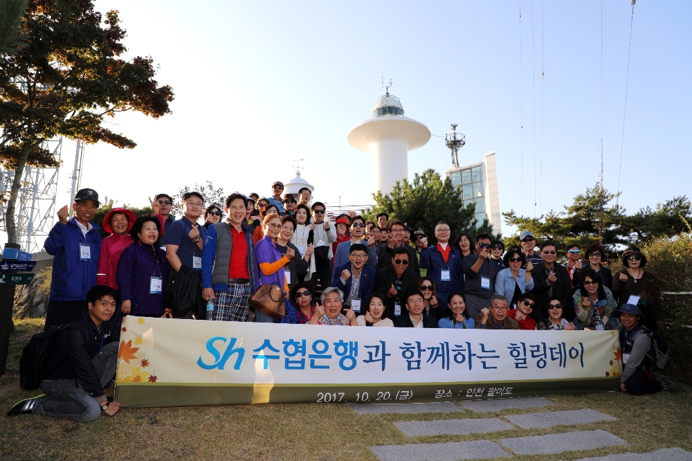 △지난 20일 Sh수협은행이 주최한 ‘우수고객 초청 힐링데이’ 행사의 참가자들이 팔미도 등대 앞에서 기념사진을 촬영하고 있다. / 사진제공=수협은행