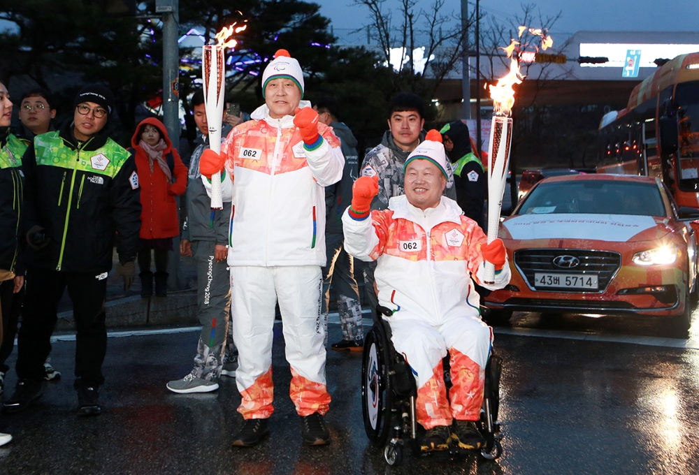 하나금융그룹은 지난 8일 오후 강릉시청에서 진행된 '2018 평창 동계패럴림픽대회 성화봉송'에 참여했다고 밝혔다. 성화봉송 주자로 참여한 김정태 하나금융그룹 회장(사진 왼쪽)과 전선주 대한장애인체육회 훈련육상부장(사진 오른쪽). / 사진= 하나금융지주