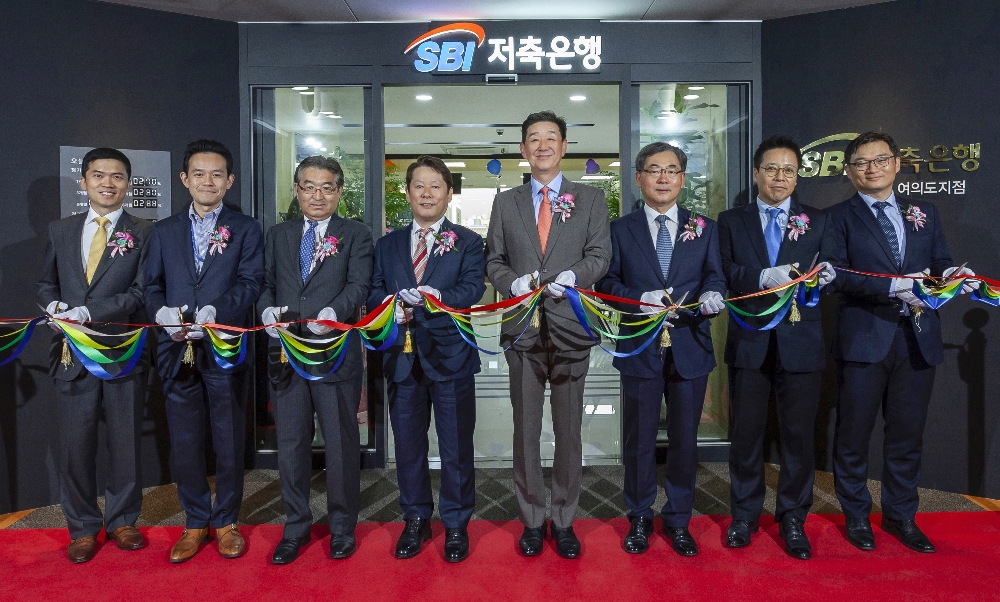 △(오른쪽부터) 진선종 기업금융1부 부장, 김문석 경영전략본부장, 박인찬 감사, 임진구 대표이사, 정진문 대표이사, 타니구치 재무심사관리본부장, 카츠치 전무, 김덕현 여의도지점장이 개점식에서 기념촬영을 하고 있다./사진=SBI저축은행