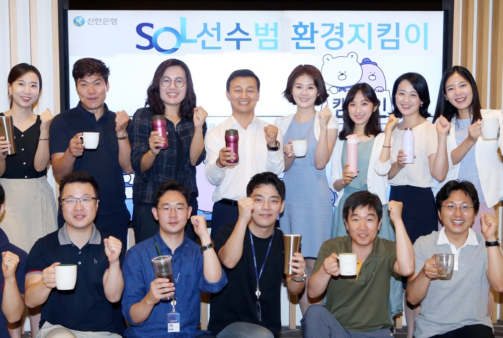 신한은행은 3일 서울 중구 소재 본점에서 1회용품 감소와 적극적인 환경보호 활동을 위한 ‘솔(SOL)선수범 환경지킴이’ 선포식을 개최했다. 김성우 부행장(뒷줄 왼쪽에서 네번째)과 임직원들이 텀블러와 머그컵을 들고 1회용품 사용을 줄이기 위해 의지를 다지고 있다. / 사진= 신한은행