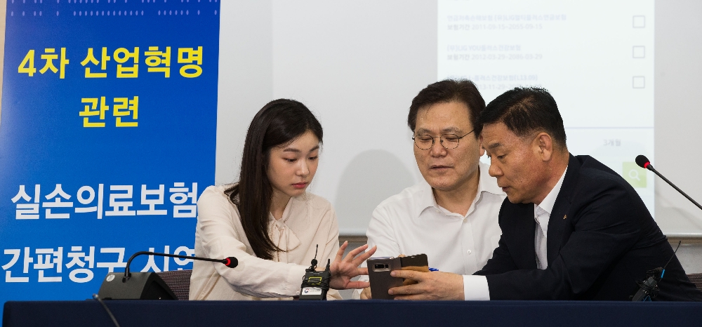 △최종구 금융위원장과 김연아 전 국가대표 피겨 선수가 실손의료보험 간편청구 앱을 시연하고 있다. / 사진=금융위원회